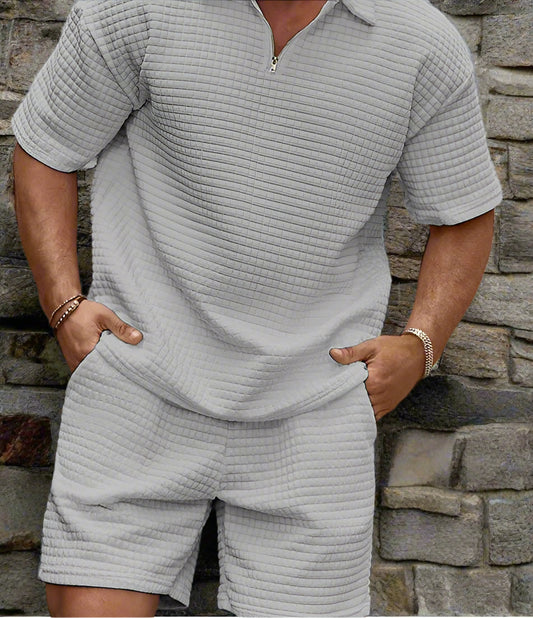 Man wearing a modern streetwear two-piece set with a short-sleeve zip-up shirt and matching shorts in textured fabric.
